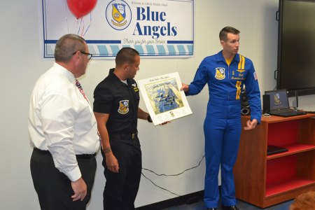 A Blue Angel visits Lemoore's Liberty Middle School delivering lessons about trumpets and the United States Navy Lt. Cmdr. Brandon Hempler and Crew Chief Jeramie Race present to Liberty Principal Ben Luis a picture of the Blue Angels flying over Yosemite National Park.